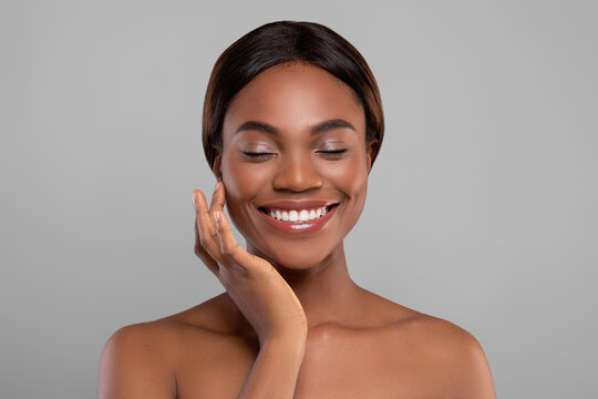 Self Care Concept. Beautiful black female with bare shoulders touching face skin