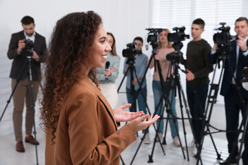 Happy African American business woman talking to group of journalists indoors