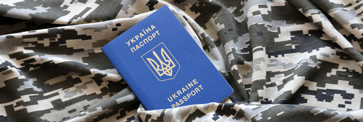 Ukrainian foreign passport on fabric with texture of military pixeled camouflage. Cloth with camo...