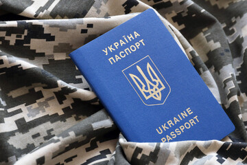 Ukrainian foreign passport on fabric with texture of military pixeled camouflage. Cloth with camo...