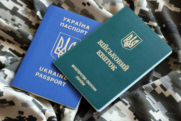 Ukrainian military ID and foreign passport on fabric with texture of pixeled camouflage. Cloth with...