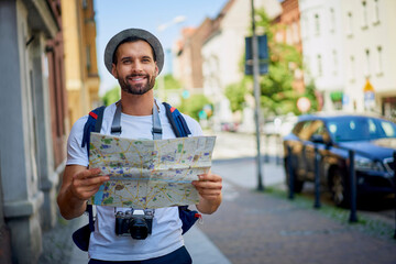 Male tourist with map in visiting European city in summer..Young man exlporing city