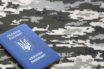 Ukrainian foreign passport on fabric with texture of military pixeled camouflage. Cloth with camo...