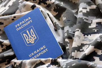 Ukrainian foreign passport on fabric with texture of military pixeled camouflage. Cloth with camo...
