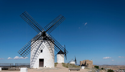 Windmills and old castle in Consuegra, Toledo, Castilla La Mancha, Spain. Several windmills and castle on a hill under a little cloudy sky