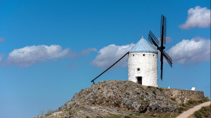 Windmills and old castle in Consuegra, Toledo, Castilla La Mancha, Spain. Blade windmill on a high with cloudy sky background