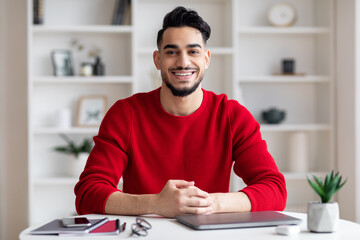 Portrait Of Smiling Handsome Arab Man Sitting At Desk In Home Office