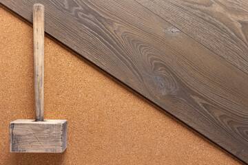 Laminate wood floor on cork background texture and hammer. Wooden laminate floor