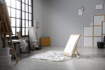 Stylish artist's studio interior with canvas, white fabric and brushes