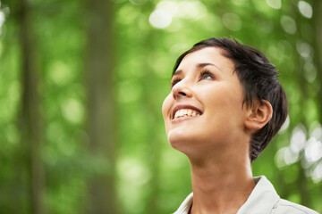 A love of all things in nature. A closeup shot of an attractive young woman looking upwards into...