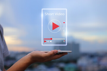 Short Video marketing concept.Man hands holding mobile phone showing virtual short video player with blurred city as background - obrazy, fototapety, plakaty