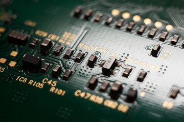 Macro photo of a green computer printed circuit board with selective focus on electronic components.