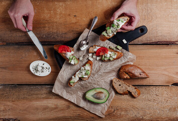 Sandwiches with pasta,avocado, tomato. Whole grain bread. Vegan sandwich from vegetables on black cutting board. Wooden background
