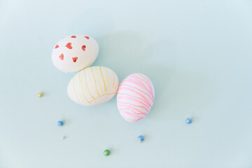 Close-up of three white Easter eggs with a pattern of hearts and waves on a blue background with decor. Orthodox Easter with a space to copy. High quality photo