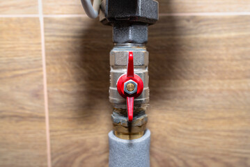Open water valves connecting to the gas boiler in a modern home boiler room with ceramic tiles.