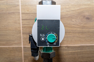 Water circulation pump for underfloor heating in a modern gas boiler room lined with ceramic tiles,...