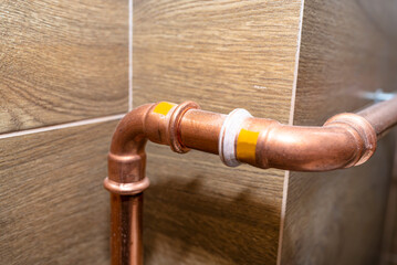 Copper pipe elbow for for natural gas installations, attached to a wall in a boiler room lined with...
