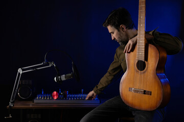 Man sitting and playing guitar. Musician in record studio holding acoustic guitar