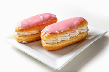 Glazed buns with cream on a plate on a white background. Photo