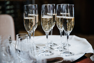 Stylish golden champagne in glasses, alcohol drink on tray serving at reception.