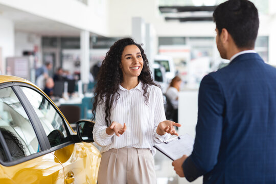 Female customer having conversation with sales associate at auto dealership