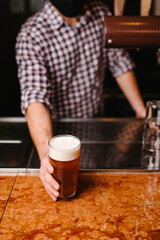 Bartender holding a glass of beer at the bar