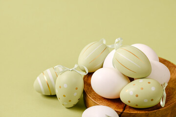 Green and white Easter eggs in a wooden plate on a green background. Green and white Easter eggs. Copy space. Spring mood.
