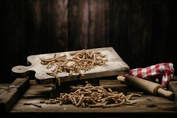 Raw pasta busiate on wooden table
