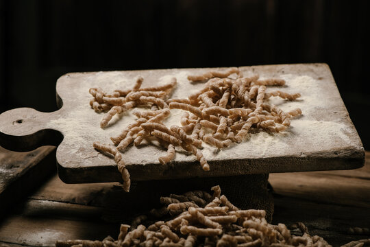 Raw pasta busiate on wooden table
