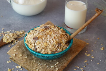 Oatmeal in a green bowl with a glass of milk on a gray background. A healthy, nutritious morning breakfast. Oat milk. Healthy vegan non-dairy organic drink with flakes.