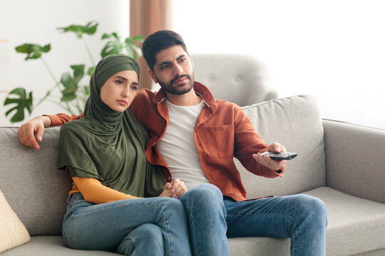 Discontented Middle Eastern Spouses Watching Television Sitting At Home
