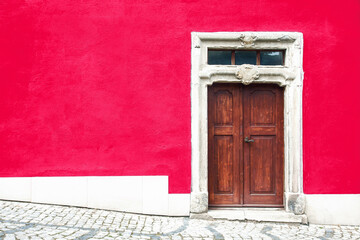 Wooden door home entrance. Italian architecture background. Vibrant color pink wall facade. Small town house exterior. Street of European city building.	