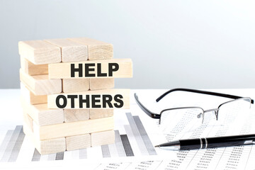 HELP OTHERS is written on wooden blocks on a chart background