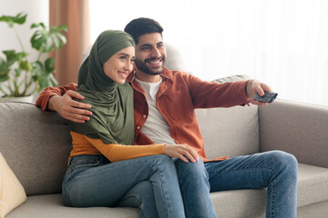 Side View Of Happy Middle Eastern Spouses Watching TV Indoors