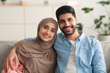 Smiling Middle Eastern Couple Embracing Sitting On Couch At Home