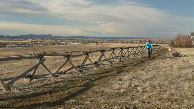 senior male cyclist is riding a gravel bike on a dirt muddy trail with a view of foothills and Front Range of Rocky Mountains in Fort Collins, Colorado