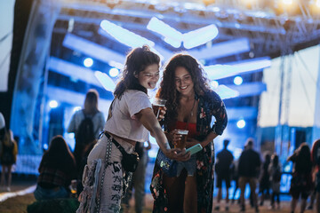 Two beautiful friends taking selfie with a samrtphone on a music festival