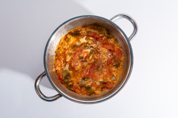 Top view close-up shot of Turkish traditional dish pepper menemen dish with selective focus on gray background in isolated setting.
