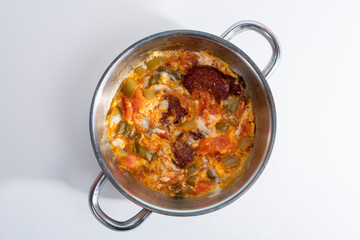 Close-up shot of top angle shot with selective focus on gray background, isolated on gray background, shot of Turkish traditional food menemen with sausage.