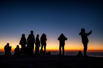 Silhouette of unidentified people at the top of mountain waiting for sunrise
