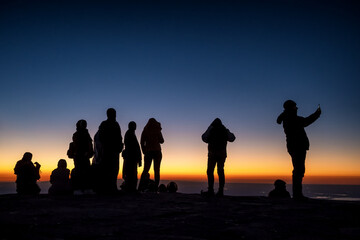 Fototapeta premium Silhouette of unidentified people at the top of mountain waiting for sunrise
