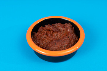 Cropped view of spicy breakfast tomato paste shot with selective focus from opposite or side view on isolated area blue background.