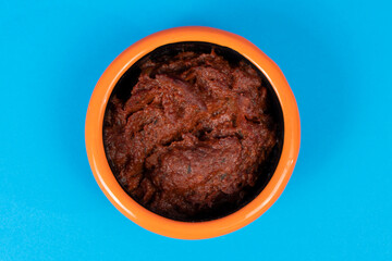 Cropped view of spicy breakfast tomato paste shot with selective focus from overhead angle on blue background in isolated area.