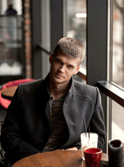 handsome man sitting in a cafe by the window