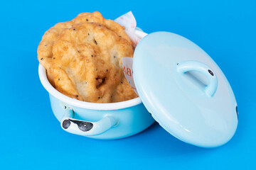 Close-up shot of pancakes and saucepan with blue lid with selective focus from opposite or side view in isolated area.