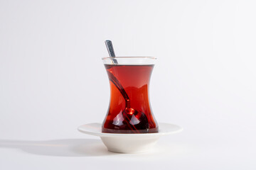 Cropped view of fresh tea in glass cup on white plate shot on isolated white background.