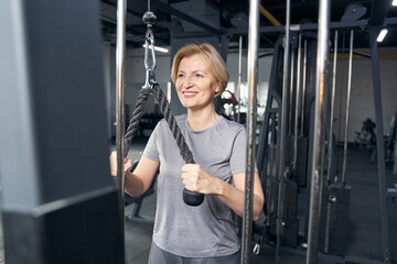 Fototapeta na wymiar Cheerful woman using gym equipment during training