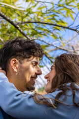 A guy and a girl looking at each other in the park. A loving couple smiles and relaxes on nature. Heterosexual couple human love relationship concept. vertical concept