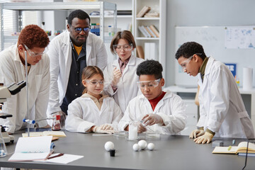 Diverse group of children wearing lab coats in chemistry class while enjoying science experiments - Powered by Adobe