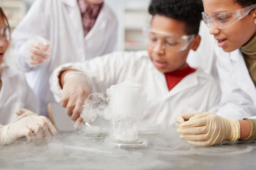 Close up of foaming liquid in beaker glass on table in school chemistry lab, copy space